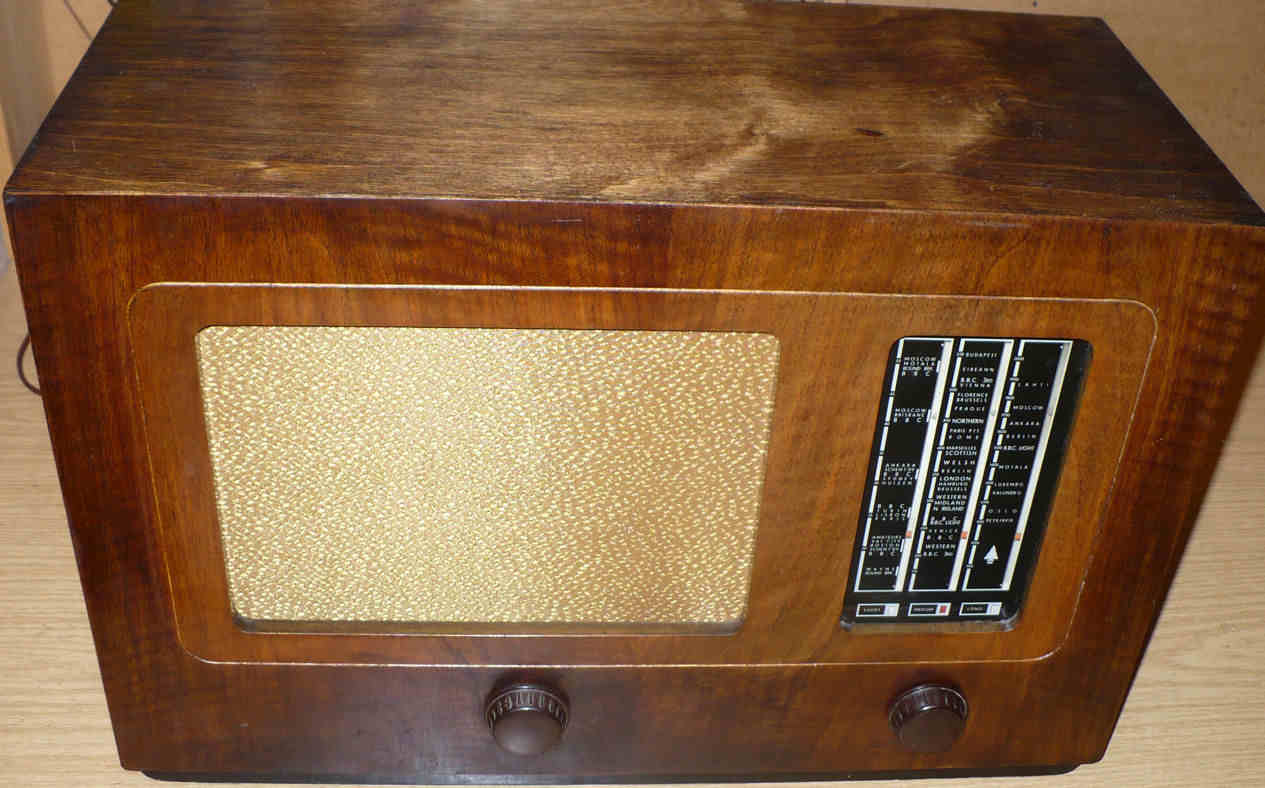 Walnut cabinet radio with a gold speaker cloth on the left, a vertical tuning scale on the right and two brown knobs below