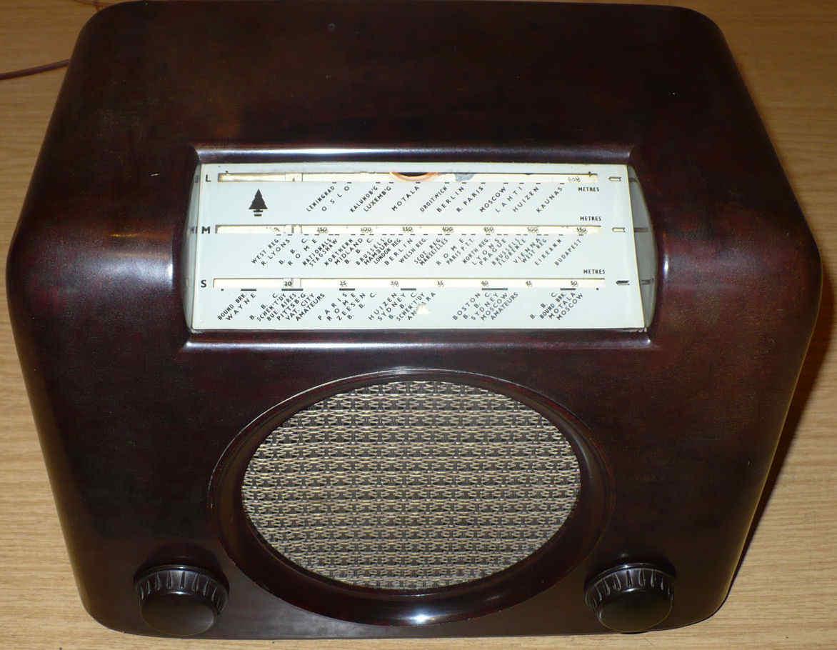 Dark brown Bakelite radio with a cream tuning scale across the top, a round speaker grille below it and a knob at each side
