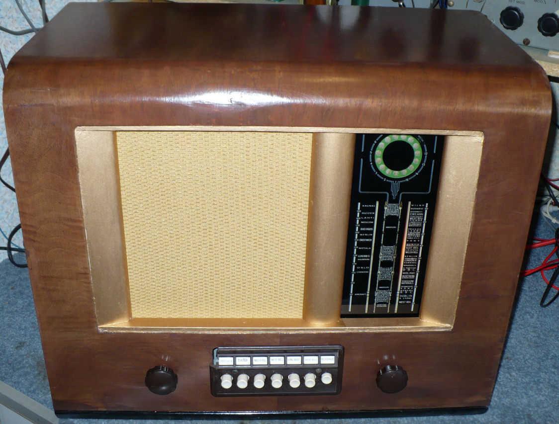 Walnut cabinet with a gold speaker cloth on the left, a black vertical tuning scale on the right and a row of white push buttons below