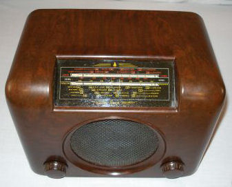 Rounded brown Bakelite radio with a tuning scale at the top, a round speaker grille below it and a knob at each lower corner