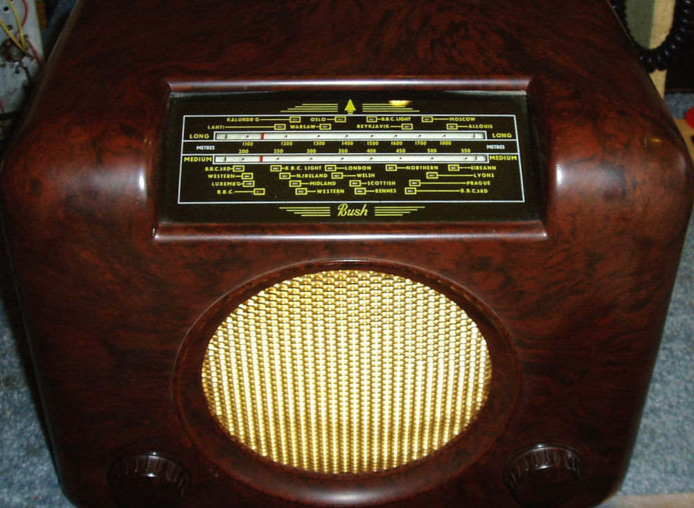 Square-shouldered brown Bakelite radio with a black and gold tuning scale at the top and a large round gold speaker grille