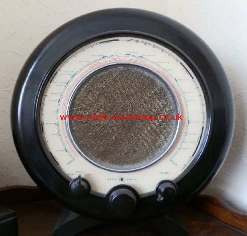 Round black Bakelite radio with a circular tuning scale around a central speaker grille and three knobs underneath