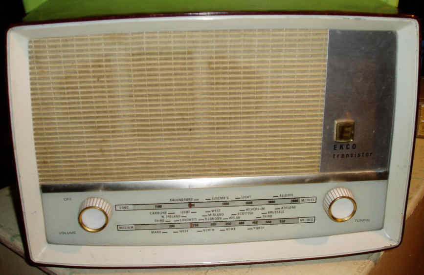 Cream and grey plastic radio with a large speaker grille above a wide tuning scale and two gold-coloured knobs