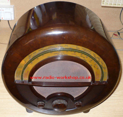 Round brown Bakelite radio with a curved tuning scale across the middle and brown knobs below