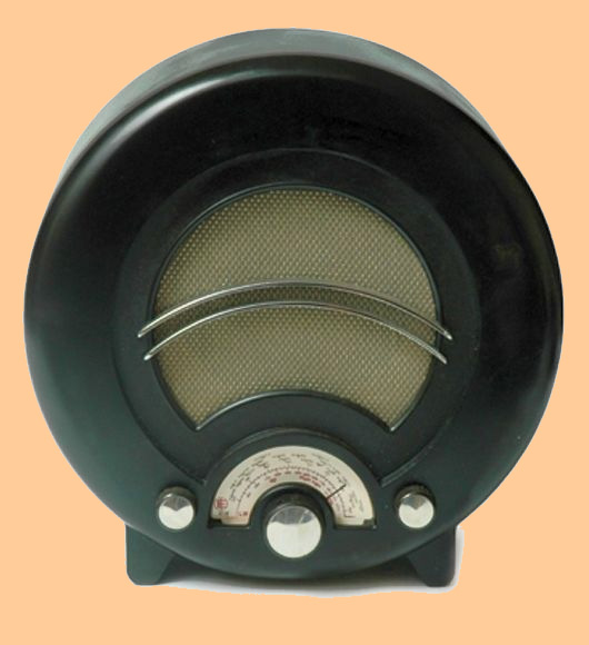 Round black Bakelite radio with a circular speaker grille crossed by two curved chrome bars, and a small tuning dial and knobs beneath
