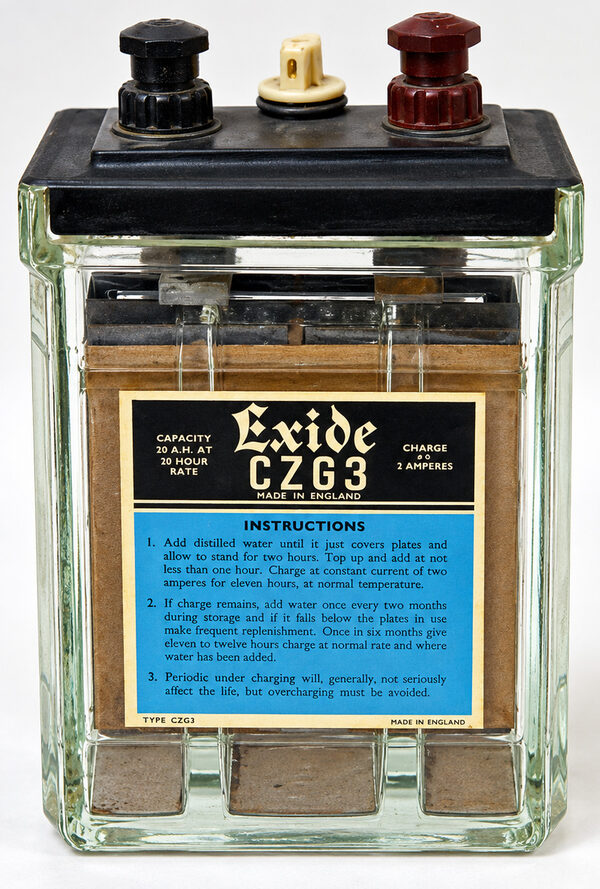 Exide CZG3 2 volt accumulator in a glass case with a black lid, two terminals and a charging instructions label