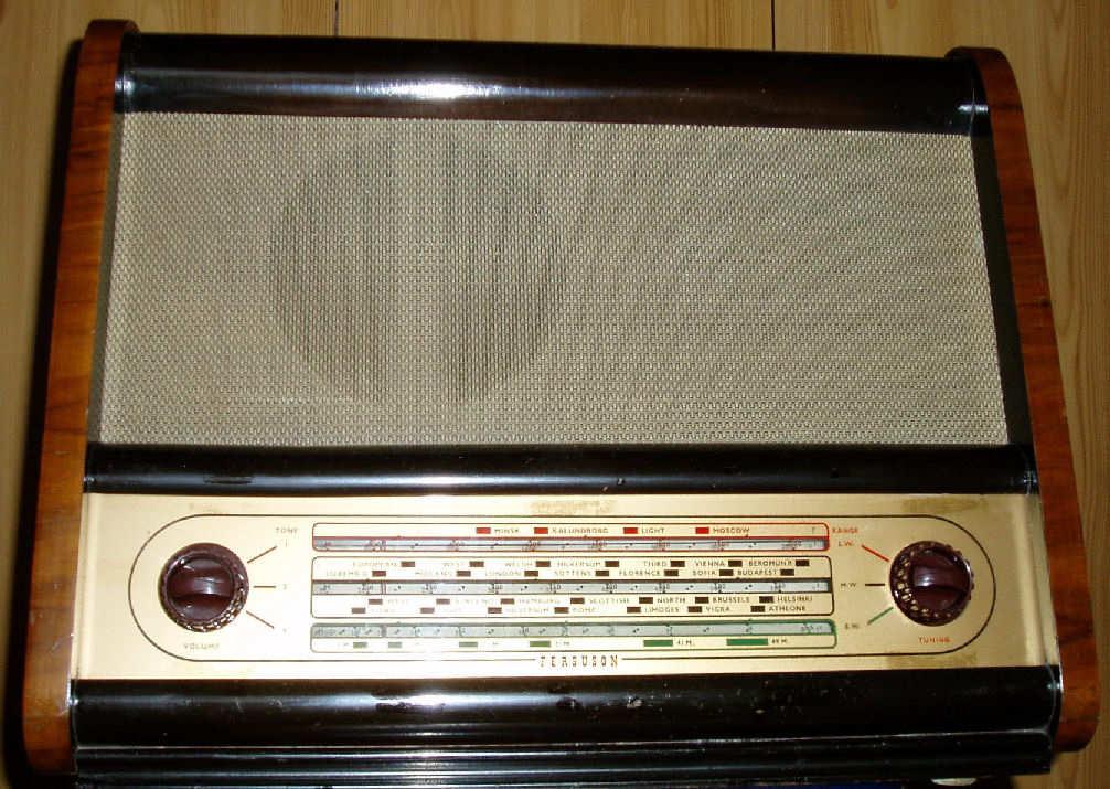 Walnut and black radio with a large grey speaker cloth above a cream tuning panel, with a red-brown knob at each end