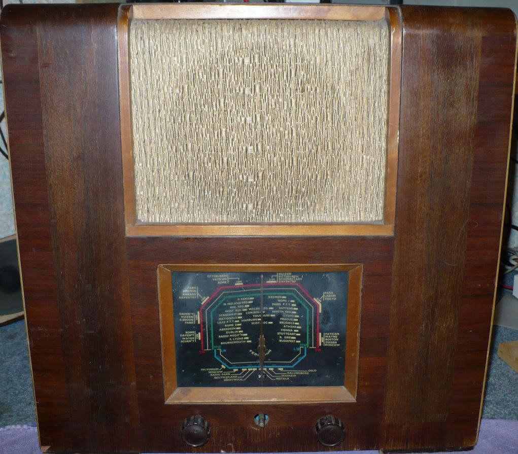 Tall walnut cabinet with a square speaker cloth above a small black tuning dial and two knobs