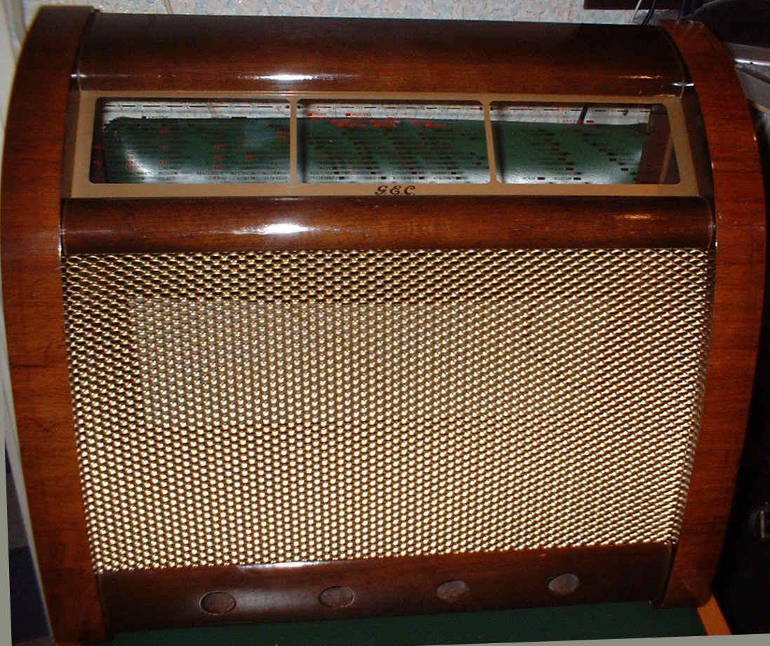 Walnut cabinet with a tilted three-panel tuning scale above a large gold mesh speaker grille