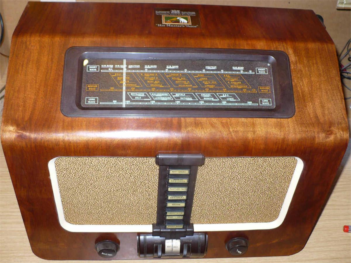 Walnut cabinet with a dark tuning scale at the top, a cream speaker cloth with a vertical strip of push buttons and two knobs below