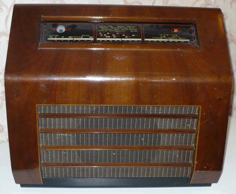 Walnut cabinet with a tuning scale along the top and a speaker grille of horizontal slots covering the front