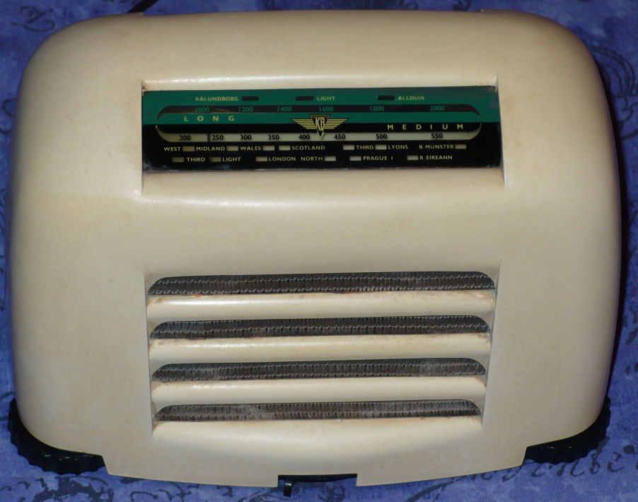 Cream plastic radio with a rounded top, a green tuning scale and horizontal speaker slots below it