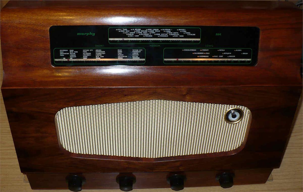 Walnut cabinet with a long tuning scale across the top, a diamond-shaped cream speaker grille and four black knobs along the bottom