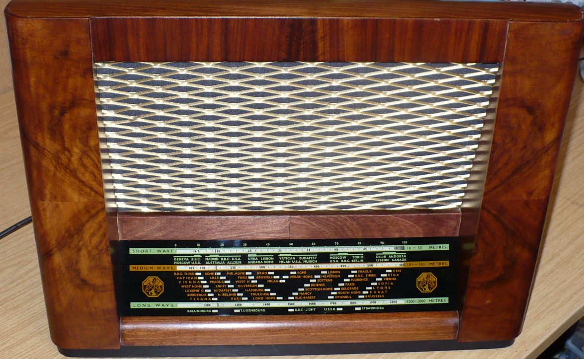 Walnut cabinet with a diamond-patterned metal speaker grille above a black and green tuning scale