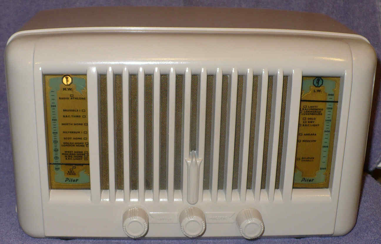 Cream Bakelite radio with vertical speaker slots in the middle, a yellow wavelength panel on each side and three knobs below