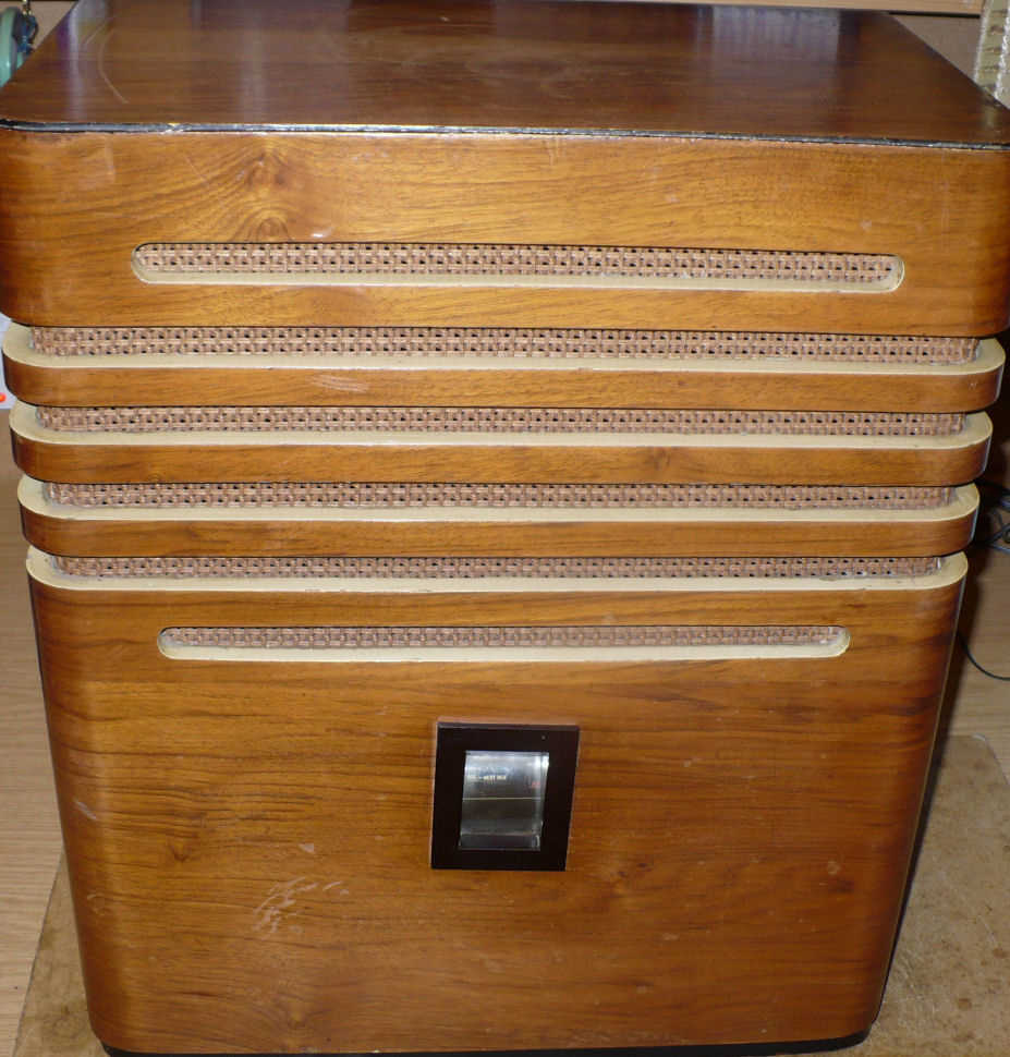 Tall walnut cabinet with rounded corners and stacked horizontal speaker slots above a small black panel